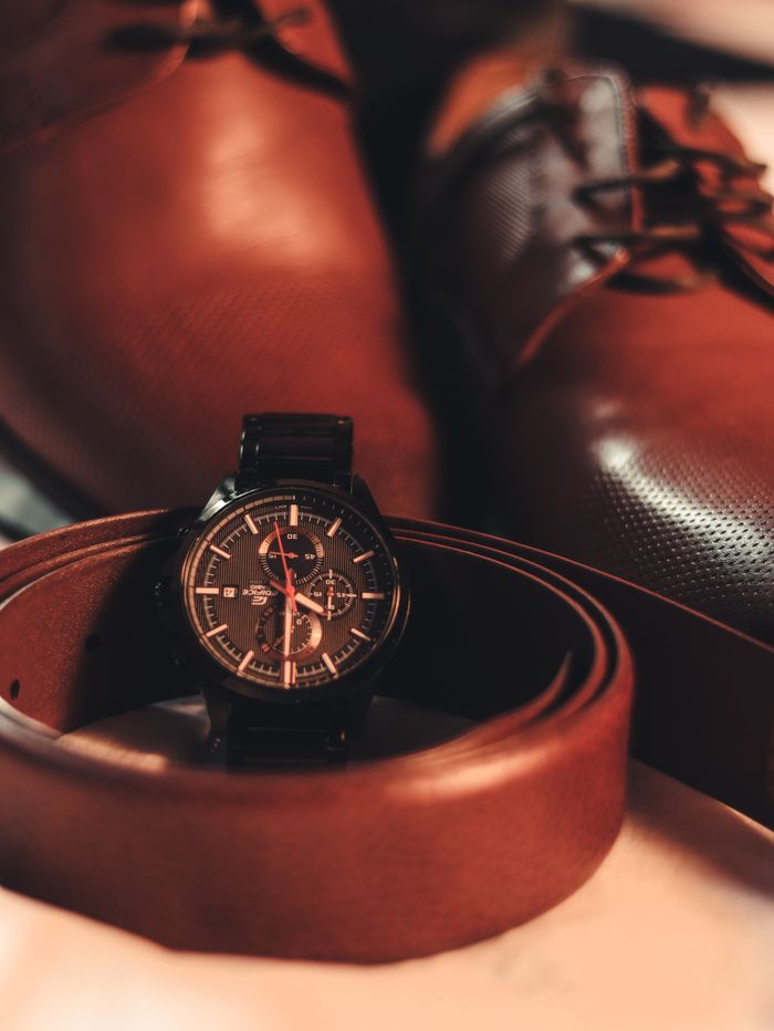 bedroom-bliss Close-up of a stylish men's wristwatch with leather shoes and belt, highlighting elegance and fashion.