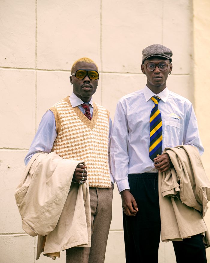 about-us-02 Two men pose in vintage style attire, showcasing retro fashion with unique accessories.